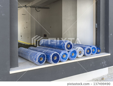 Rolls of reinforcing mesh for underfloor heating installation on window sill at construction site Rolls of reinforcing mesh for underfloor heating installation on window sill at construction site 137499490