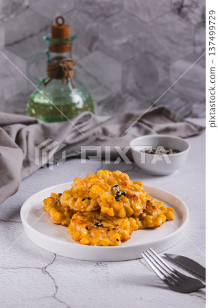Delicious corn fritters with herbs on a plate on the table vertical view Delicious corn fritters with herbs on a plate on the table vertical view 137499729