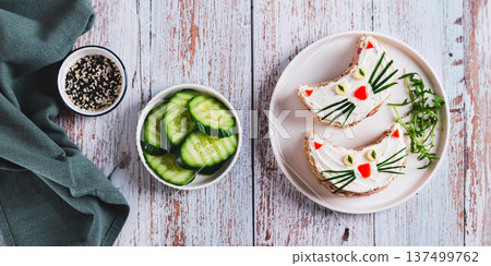 Sandwiches with sausage decorated with vegetables on a plate on the table top view web banner Sandwiches with sausage decorated with vegetables on a plate on the table top view web banner 137499762