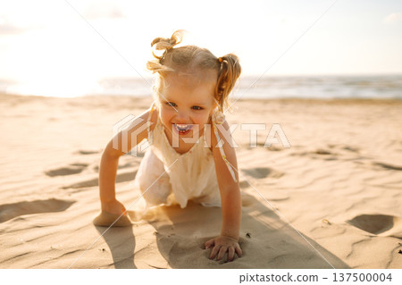 Young girl joyfully plays on the sandy beach during sunset, enjoying a carefree moment by the ocean Young girl joyfully plays on the sandy beach during sunset, enjoying a carefree moment by the ocean 137500004