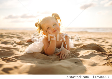 Young girl joyfully plays on the sandy beach during sunset, enjoying a carefree moment by the ocean 137500007