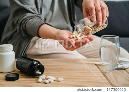 Sickness and health issues. Woman holding a pill bottle at home, healthy care and treatment concept. Sickness and health issues. Woman holding a pill bottle at home, healthy care and treatment concept. 137500013