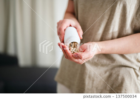 Woman pouring a pile of pills, capsules from a bottle in hand. Prescription medication, treatment sickness concept Woman pouring a pile of pills, capsules from a bottle in hand. Prescription medication, treatment sickness concept 137500034