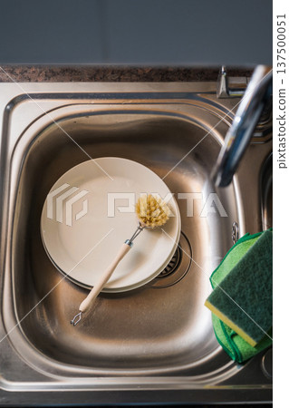 Authentic sustainability concept. Wooden brush for washing dishes in the kitchen sink. Eco friendly, zero waste or conscious consumption concept. Authentic sustainability concept. Wooden brush for washing dishes in the kitchen sink. Eco friendly, zero waste or conscious consumption concept. 137500051