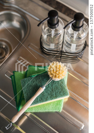 Authentic sustainability concept. Wooden brush and plastic sponge for washing dishes in the kitchen. Eco friendly, zero waste or conscious consumption concept. Authentic sustainability concept. Wooden brush and plastic sponge for washing dishes in the kitchen. Eco friendly, zero waste or conscious consumption concept. 137500052