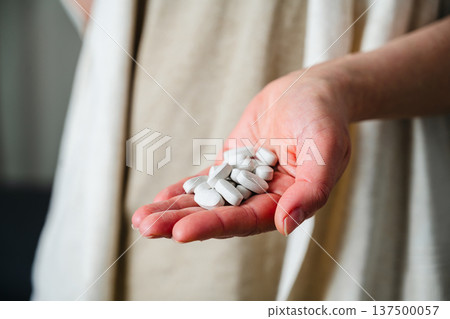 Woman holding a pile of pills in hand. Prescription medication, treatment and sickness concept, seasonal flu and cold 137500057
