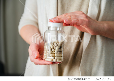 Woman holding a bottle with capsules pills. Prescription medication, treatment sickness, seasonal cold flu concept 137500059