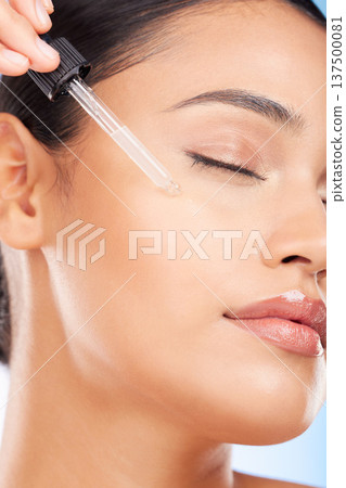 Skincare, beauty and woman with serum in pipette for anti aging or skin glow on blue background. Cosmetics, facial detox and face of model with solution or collagen product for dermatology in studio. Skincare, beauty and woman with serum in pipette for anti aging or skin glow on blue background. Cosmetics, facial detox and face of model with solution or collagen product for dermatology in studio. 137500081