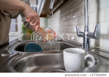 Zero waste concept. Eco-friendly kitchen wooden brush. Woman washing dishes with bamboo brush. Waste-free, eco-friendly concept 137500094