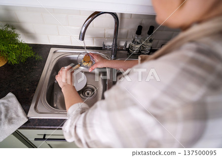 Eco-friendly kitchen wooden brush. Woman washing dishes with bamboo brush. Waste-free, eco-friendly concept 137500095