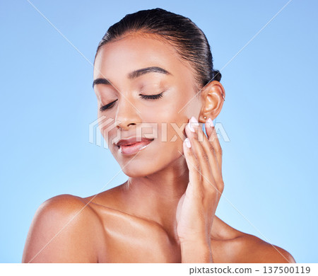 Woman, touching face and natural beauty, skincare and cosmetic care isolated on blue background, Indian model with satisfaction, wellness and calm, zen and dermatology with skin glow in a studio Woman, touching face and natural beauty, skincare and cosmetic care isolated on blue background, Indian model with satisfaction, wellness and calm, zen and dermatology with skin glow in a studio 137500119