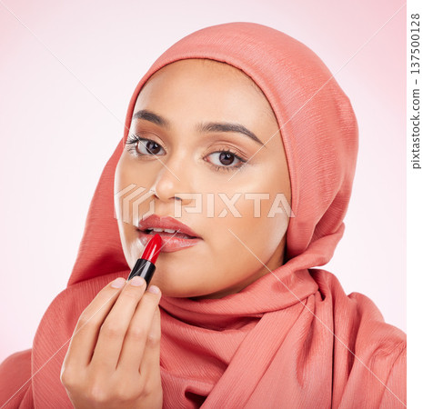 Portrait, beauty or lipstick with an arab woman closeup in studio on a pink background for cosmetics. Face, makeup and muslim with a confident young model in an hijab to apply a product for red color Portrait, beauty or lipstick with an arab woman closeup in studio on a pink background for cosmetics. Face, makeup and muslim with a confident young model in an hijab to apply a product for red color 137500128