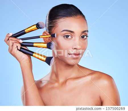 Makeup, brush and woman, beauty and portrait with cosmetic tools isolated on blue background. Foundation, powder and cosmetology, skin glow and wellness with equipment and grooming in a studio Makeup, brush and woman, beauty and portrait with cosmetic tools isolated on blue background. Foundation, powder and cosmetology, skin glow and wellness with equipment and grooming in a studio 137500269