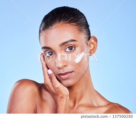 Skincare, cream and health with face of woman in studio for beauty, facial or moisturizer. Spa treatment, lotion and collagen with portrait of person on blue background for makeup, glow or sunscreen Skincare, cream and health with face of woman in studio for beauty, facial or moisturizer. Spa treatment, lotion and collagen with portrait of person on blue background for makeup, glow or sunscreen 137500280