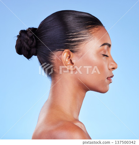 Woman, skincare and profile of natural beauty or shine on skin from cosmetics on blue background in studio with calm model. Dermatology, facial and healthy glow from makeup, wellness or self care Woman, skincare and profile of natural beauty or shine on skin from cosmetics on blue background in studio with calm model. Dermatology, facial and healthy glow from makeup, wellness or self care 137500342