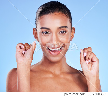 Woman, portrait and floss teeth in studio for healthy dental care, gum gingivitis and plaque on blue background. Happy indian model and oral thread for cleaning mouth, fresh breath and tooth hygiene Woman, portrait and floss teeth in studio for healthy dental care, gum gingivitis and plaque on blue background. Happy indian model and oral thread for cleaning mouth, fresh breath and tooth hygiene 137500380