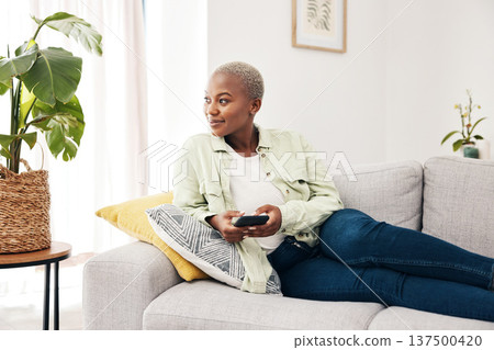 Woman, smile and thinking with smartphone on sofa for social media post, digital contact and user connection. Happy african person, mobile and idea to download app, search subscription or web at home Woman, smile and thinking with smartphone on sofa for social media post, digital contact and user connection. Happy african person, mobile and idea to download app, search subscription or web at home 137500420