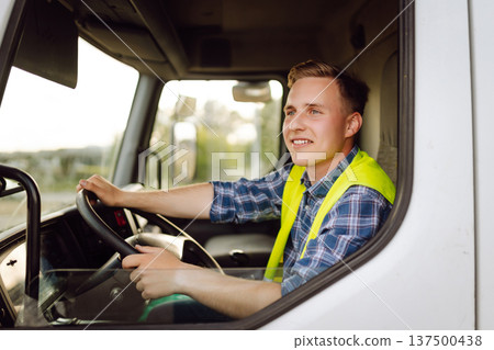 Driver at the wheel of a truck at work. Driver or forwarder on truck on a transshipment point 137500438
