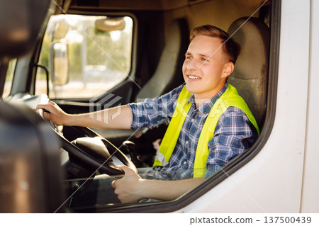 Driver at the wheel of a truck at work. Driver or forwarder on truck on a transshipment point 137500439