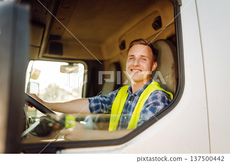 Driver at the wheel of a truck at work. Driver or forwarder on truck on a transshipment point 137500442
