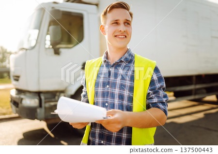 Portrait of truck driver in casual clothes standing in front of truck vehicles. Transport industry. 137500443