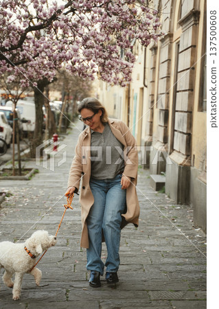 Woman Enjoys Walk with Dog on Charming Street Woman Enjoys Walk with Dog on Charming Street 137500608