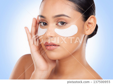 Portrait, skincare and eye mask with a natural woman in studio on a blue background for antiaging treatment. Face, beauty and wellness product with a young model at the salon for a facial application Portrait, skincare and eye mask with a natural woman in studio on a blue background for antiaging treatment. Face, beauty and wellness product with a young model at the salon for a facial application 137500955