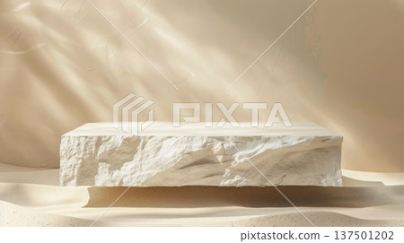 A smooth, rectangular marble block rests on sand with sunlight casting dynamic, rippling shadows across its surface. 137501202