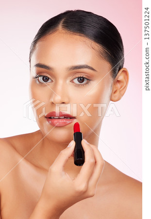 Portrait, beauty and makeup with a woman closeup on a pink background in studio for luxury cosmetics. Aesthetic, lipstick or product with a young model getting ready to apply red lipgloss to her face 137501224