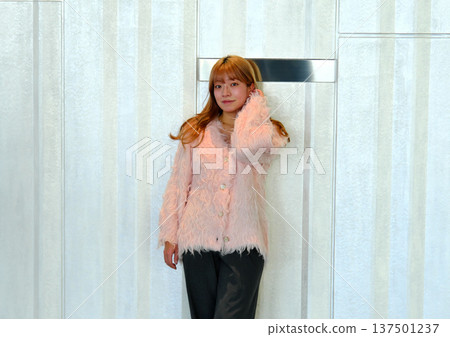 A female model posing in a modern space. A feminine indoor portrait featuring a pink knit. A female model posing in a modern space. A feminine indoor portrait featuring a pink knit. 137501237