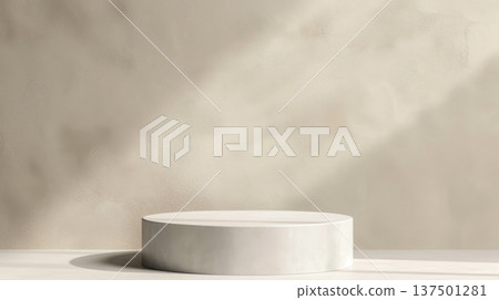 Round minimalist display stand illuminated by soft natural light, casting subtle shadows on a plain neutral background. 137501281