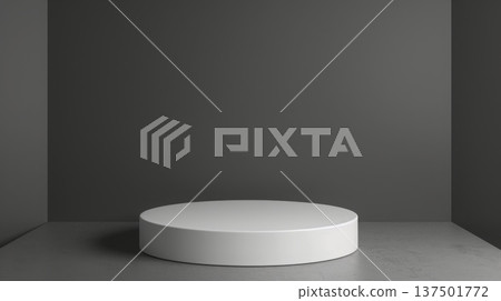A white cylindrical pedestal stands centrally in a minimalist, gray-walled room with a matching gray floor, lit softly from above. 137501772