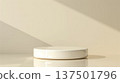A simple round white platform rests on a glossy, reflective surface, lit by natural daylight casting soft shadows from an unseen window. 137501796