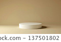A simple white round pedestal is centered on a beige surface, under soft studio lighting, showcasing elegance and minimalism. 137501802