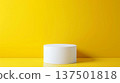 A simple white cylindrical pedestal stands prominently against a vibrant yellow backdrop, creating a striking contrast perfect for studio displays or modern interior design concepts. 137501818