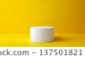 A white cylindrical pedestal stands against a vibrant yellow backdrop, illuminated by studio lighting, creating a striking minimalist composition. 137501821