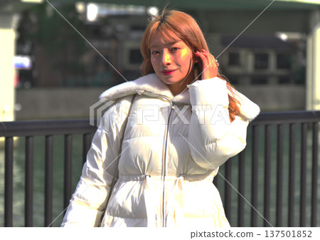 冬日里,一位女模特兒回頭望向城市河畔。這幅肖像畫突出了她白色的外套和河畔景色。 冬日里,一位女模特兒回頭望向城市河畔。這幅肖像畫突出了她白色的外套和河畔景色。 137501852