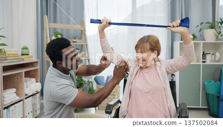 Happy senior woman with disability, physiotherapist and stretching band for muscle rehabilitation at chiropractor. Physical therapy, medical support and patient in wheelchair smile for recovery help Happy senior woman with disability, physiotherapist and stretching band for muscle rehabilitation at chiropractor. Physical therapy, medical support and patient in wheelchair smile for recovery help 137502084