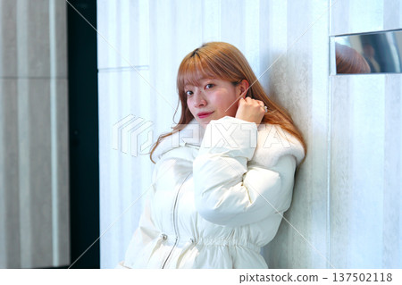 一位女模特兒倚靠在白牆上。這是一張精緻的冬季室內肖像照,她穿著乾淨的白色外套。 一位女模特兒倚靠在白牆上。這是一張精緻的冬季室內肖像照,她穿著乾淨的白色外套。 137502118