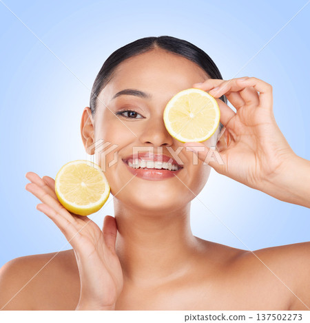 Woman, face and lemon with natural beauty, skincare and vitamin c cosmetic product isolated on blue background. Model in portrait with facial, fruit and dermatology, skin glow and citrus in studio Woman, face and lemon with natural beauty, skincare and vitamin c cosmetic product isolated on blue background. Model in portrait with facial, fruit and dermatology, skin glow and citrus in studio 137502273