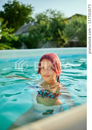 Teen girl enjoying a refreshing swim in a backyard pool during a sunny summer day Teen girl enjoying a refreshing swim in a backyard pool during a sunny summer day 137502673