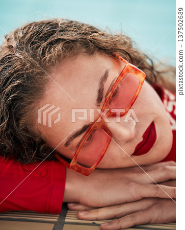Face, summer and sunglasses with a hipster woman closeup in a swimming pool for safety or style. Fashion, thinking and poolside with a young swimmer looking bored waiting alone in trendy eyewear 137502689