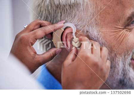 Healthcare, hands and doctor with hearing aid for man for communication support. Closeup, medical and a nurse with an implant for a patient with a disability for help with listening and conversation 137502698