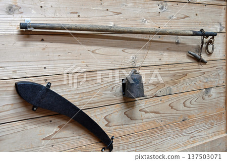 Antique beam balances and iron tools displayed on the wooden walls Antique beam balances and iron tools displayed on the wooden walls 137503071