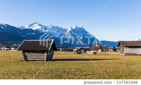 Traditional wooden hut in Bavarian countryside with snow capped Alps mountains and clear blue sky Traditional wooden hut in Bavarian countryside with snow capped Alps mountains and clear blue sky 137503366