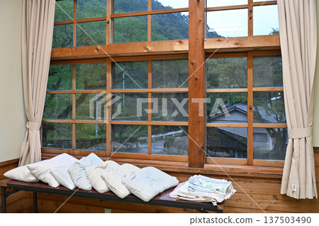 學校木造教學大樓的宿舍，配有大型木框窗戶，可欣賞到鬱鬱蔥蔥的綠植景色。 137503490