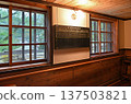A retro-style blackboard with a class timetable hanging on the wall by a warmly lit window 137503821