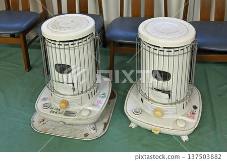 A nostalgic white cylindrical kerosene heater warms the wooden school building in winter. A nostalgic white cylindrical kerosene heater warms the wooden school building in winter. 137503882