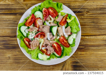 Tasty tuna salad with lettuce and fresh vegetables on wooden table. Top view Tasty tuna salad with lettuce and fresh vegetables on wooden table. Top view 137504015