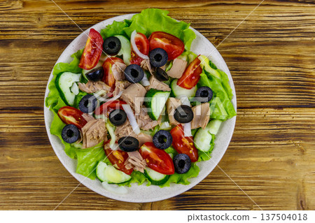 Tasty tuna salad with lettuce, black olives and fresh vegetables on wooden table. Top view Tasty tuna salad with lettuce, black olives and fresh vegetables on wooden table. Top view 137504018